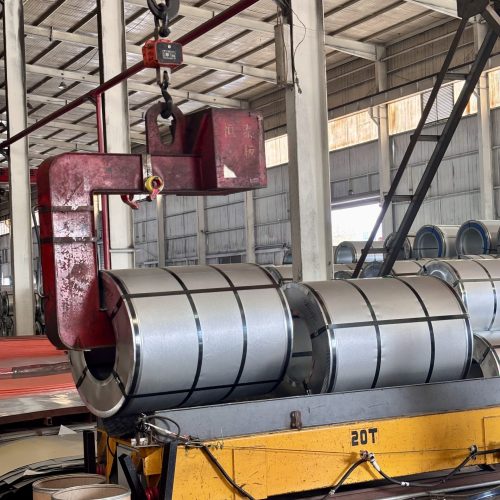 Overhead crane handling aluminum coils in factory warehouse